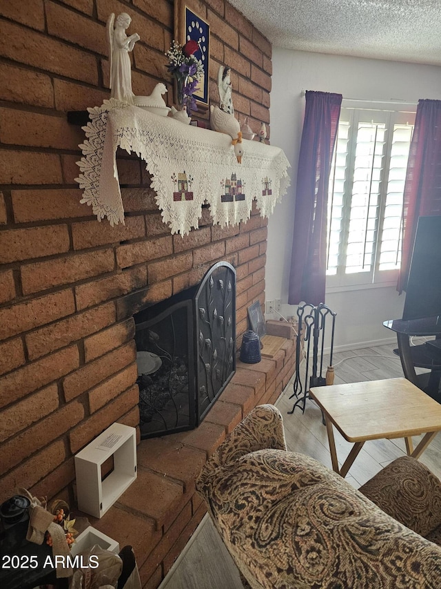 living room with hardwood / wood-style flooring, a brick fireplace, and a textured ceiling