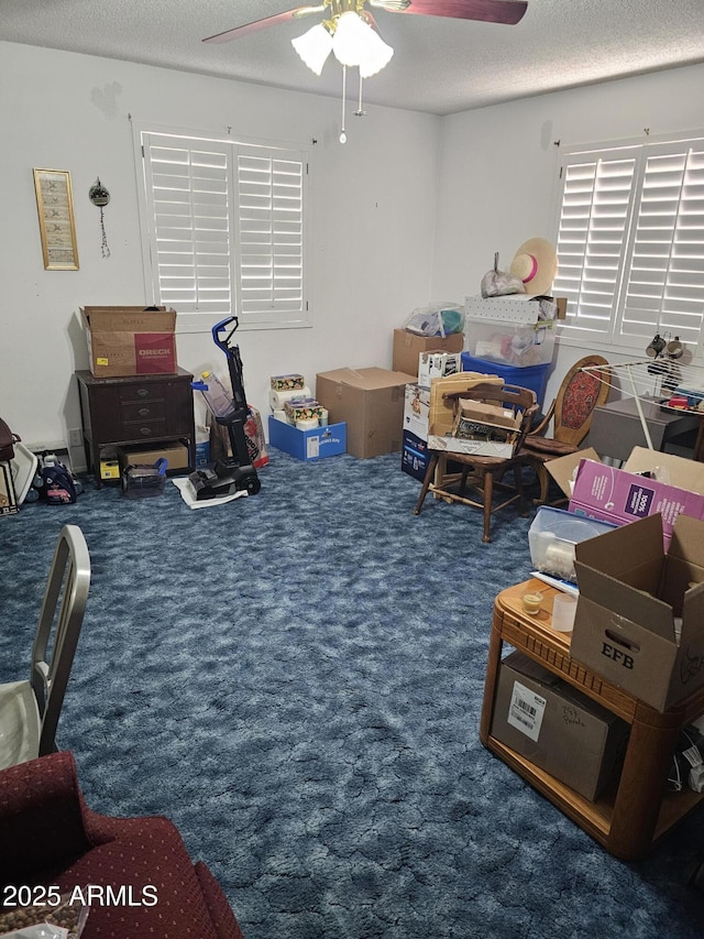 recreation room featuring ceiling fan, dark carpet, and a textured ceiling