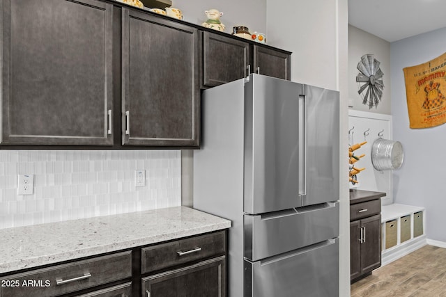 4244 Sawbuck Way, Wickenburg, AZ 85390 - kitchen with dark brown cabinetry, light stone counters, tasteful backsplash, and freestanding refrigerator