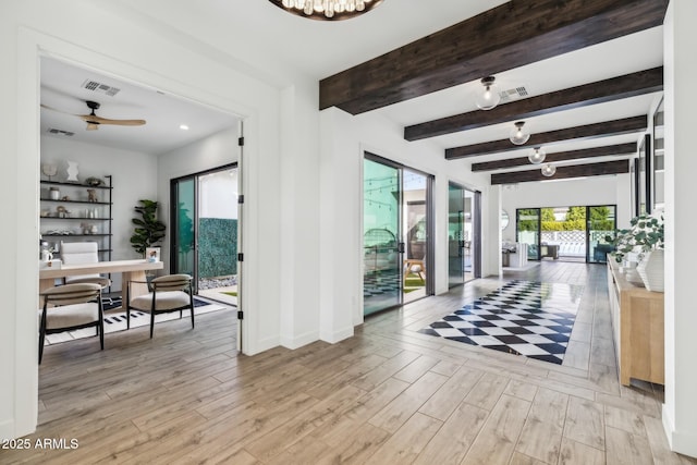 interior space with light wood finished floors, ceiling fan, visible vents, and beamed ceiling