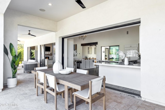 dining space featuring ceiling fan with notable chandelier, stone tile flooring, and recessed lighting