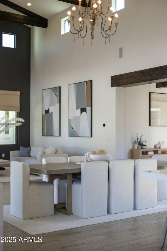 living area with beam ceiling, a towering ceiling, and wood finished floors