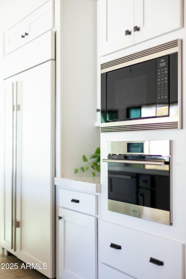 kitchen with built in appliances, light countertops, and white cabinets