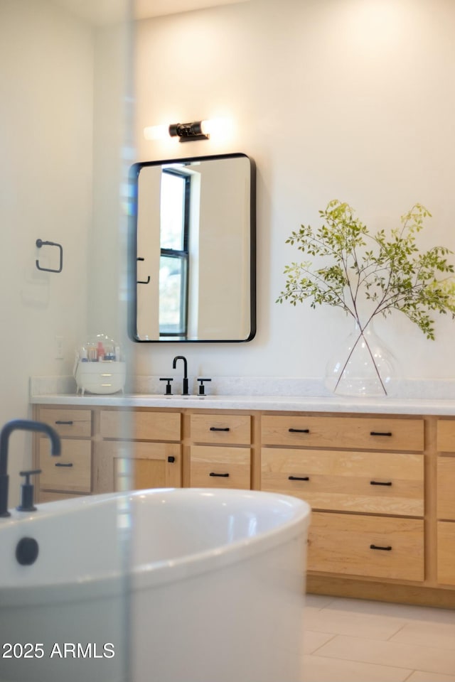 bathroom featuring tile patterned flooring, a freestanding bath, and vanity