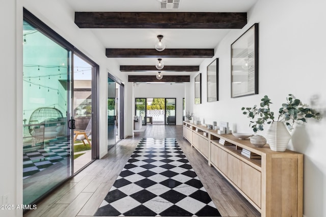 hall featuring beam ceiling, light wood-type flooring, and visible vents