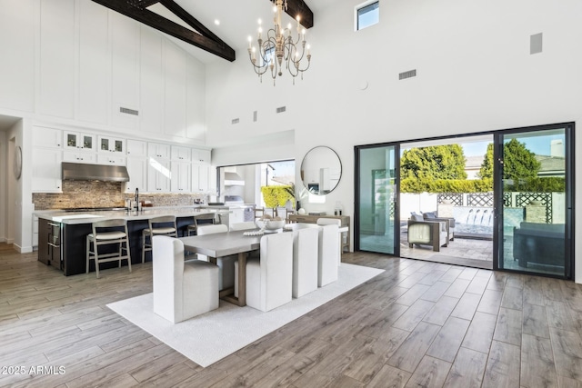 kitchen with under cabinet range hood, visible vents, light countertops, light wood-type flooring, and tasteful backsplash