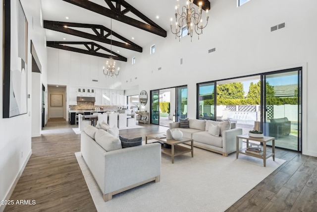 living area with baseboards, visible vents, a notable chandelier, and wood finished floors