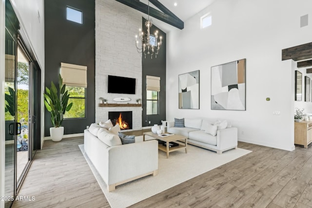 living room with light wood-style floors, a fireplace, baseboards, and a notable chandelier