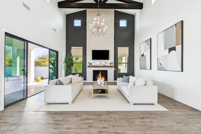 living area featuring a wealth of natural light, a notable chandelier, a fireplace, and wood finished floors