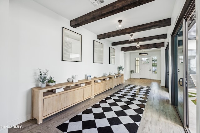 corridor with baseboards, light wood-style flooring, visible vents, and beam ceiling