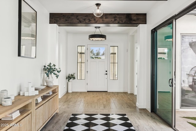 entrance foyer featuring baseboards, beamed ceiling, and light wood finished floors