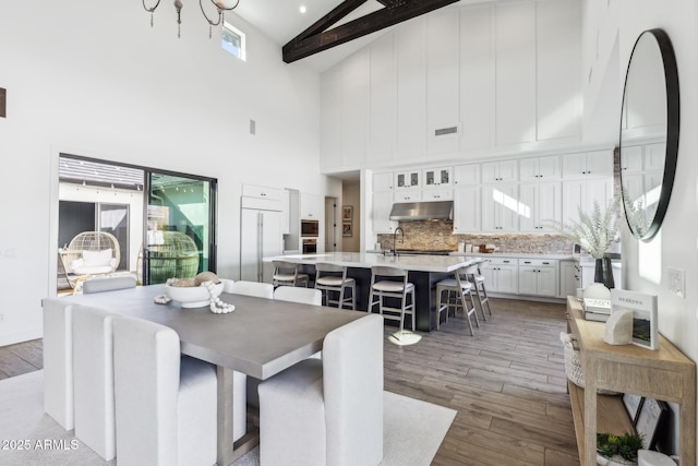 dining room featuring vaulted ceiling with beams, visible vents, and wood finished floors