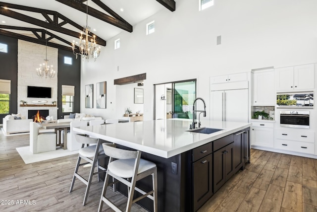 kitchen featuring paneled fridge, oven, a fireplace, a sink, and open floor plan