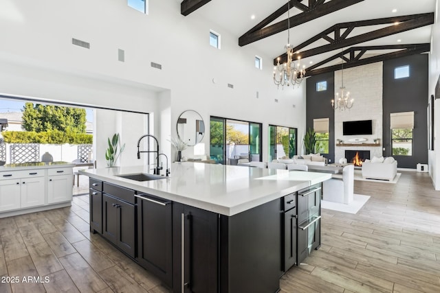 kitchen with light wood-style floors, a notable chandelier, a fireplace, and a sink