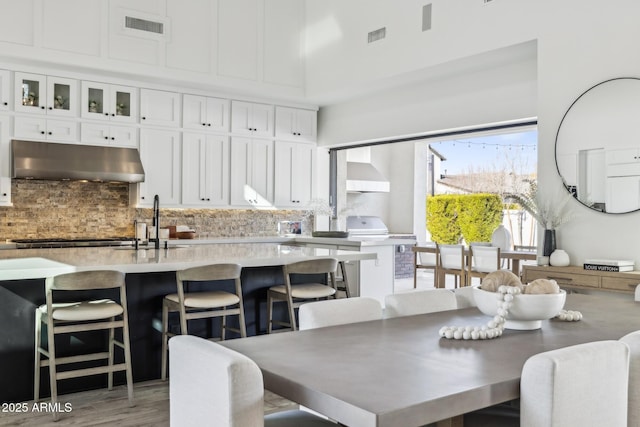 dining room featuring a towering ceiling, light wood finished floors, and visible vents