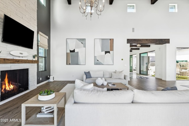 living room featuring a high ceiling, beamed ceiling, a fireplace, and wood finished floors