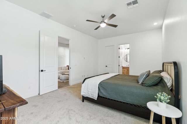 carpeted bedroom with ensuite bathroom, visible vents, and baseboards