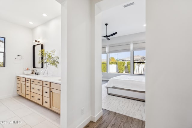 ensuite bathroom featuring double vanity, visible vents, connected bathroom, a sink, and baseboards