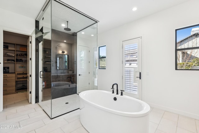 bathroom featuring a stall shower, baseboards, a soaking tub, tile patterned flooring, and a walk in closet