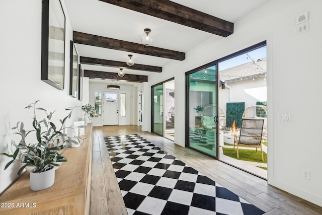 interior space featuring baseboards, wood finished floors, and beamed ceiling