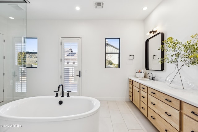 bathroom with recessed lighting, visible vents, baseboards, a freestanding bath, and vanity