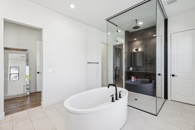 bathroom featuring recessed lighting, a shower stall, tile patterned flooring, a freestanding tub, and baseboards