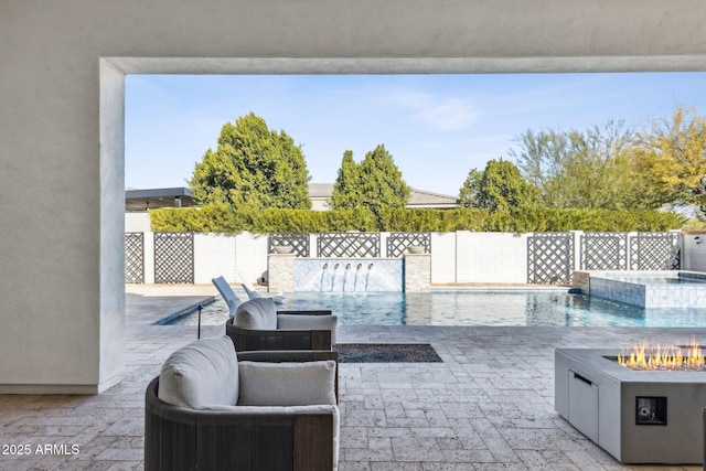 view of patio / terrace featuring an outdoor fire pit, a pool with connected hot tub, and a fenced backyard