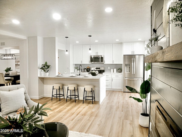 6401 E Eugie Ter, Scottsdale, AZ 85254 - kitchen featuring stainless steel appliances, a kitchen bar, white cabinets, light wood finished floors, and recessed lighting