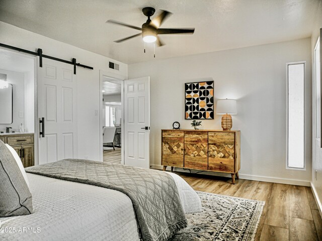 6401 E Eugie Ter, Scottsdale, AZ 85254 - bedroom with a barn door, light wood-style flooring, baseboards, a ceiling fan, and ensuite bathroom