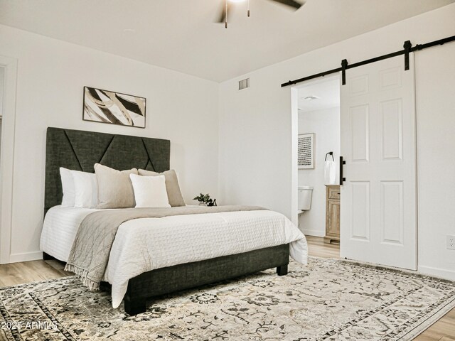 6401 E Eugie Ter, Scottsdale, AZ 85254 - bedroom featuring a barn door, light wood-style flooring, ensuite bath, baseboards, and ceiling fan