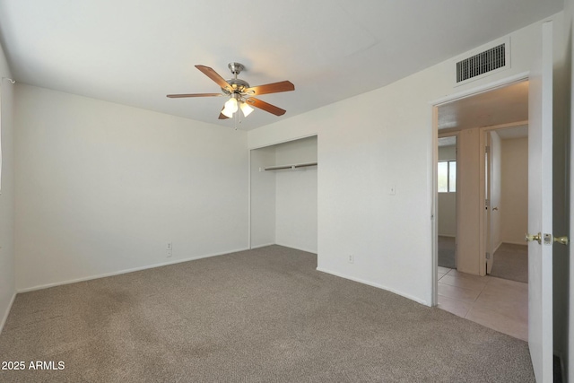 unfurnished bedroom featuring carpet flooring, visible vents, baseboards, a closet, and ceiling fan