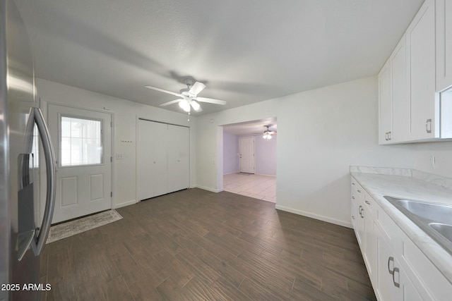 kitchen featuring ceiling fan, light countertops, stainless steel refrigerator with ice dispenser, white cabinetry, and dark wood-type flooring