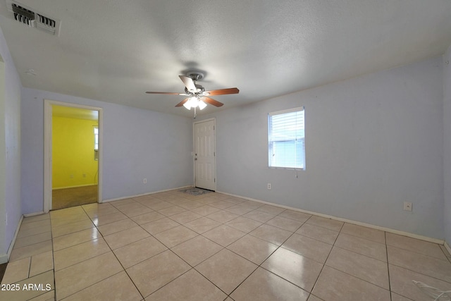 spare room featuring visible vents, a ceiling fan, light tile patterned floors, baseboards, and a textured ceiling