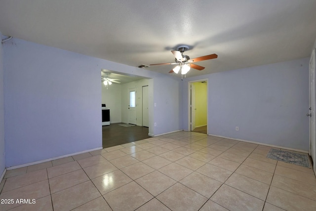 spare room featuring light tile patterned flooring, visible vents, a ceiling fan, and baseboards