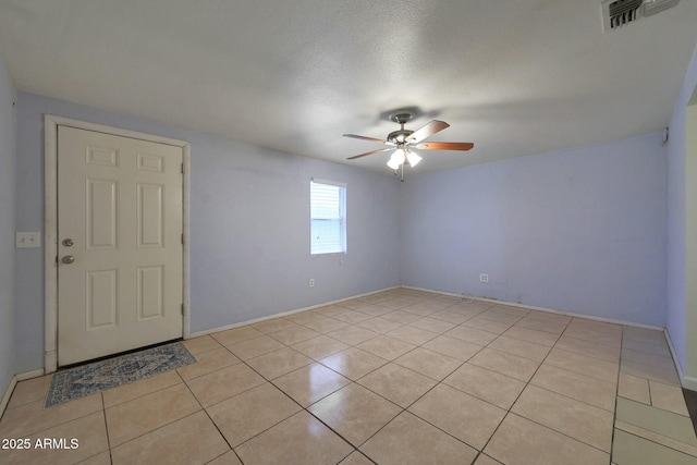 empty room with ceiling fan, baseboards, light tile patterned flooring, and visible vents