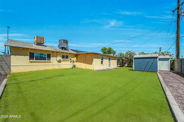 back of property featuring central air condition unit, fence, an outdoor structure, a yard, and a shed