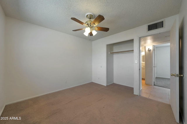 unfurnished bedroom featuring a textured ceiling, baseboards, visible vents, light colored carpet, and a ceiling fan