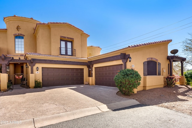 mediterranean / spanish-style home with driveway, a balcony, a tile roof, a gate, and stucco siding