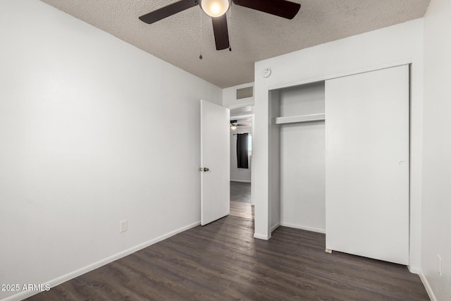 unfurnished bedroom featuring a textured ceiling, visible vents, dark wood finished floors, and a closet