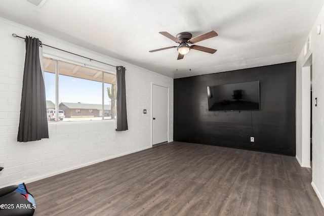 interior space featuring baseboards, ceiling fan, wood finished floors, and brick wall