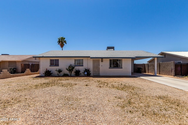 single story home featuring brick siding, fence, driveway, and a carport
