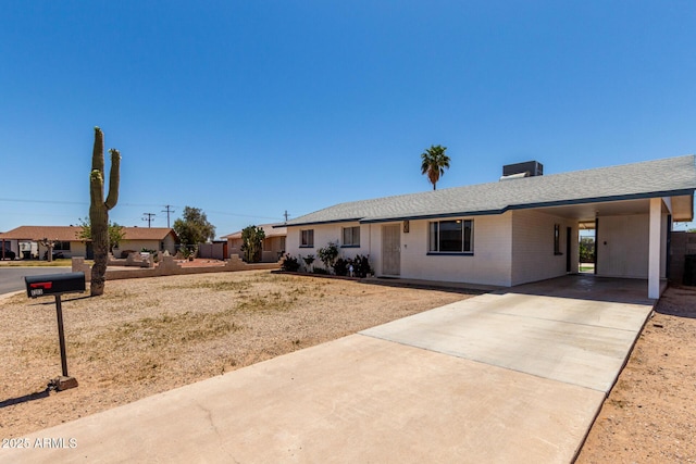 ranch-style house with brick siding, roof with shingles, driveway, and an attached carport