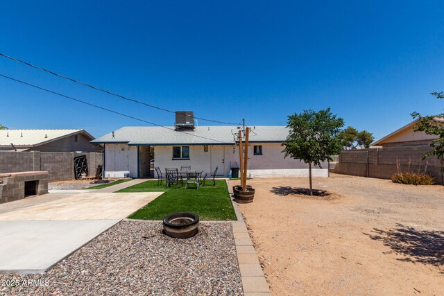 rear view of house with cooling unit, a patio, a fenced backyard, a shingled roof, and a lawn