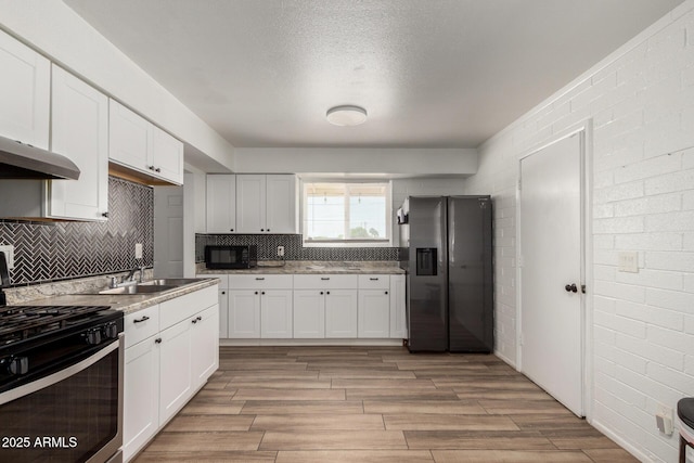 kitchen with black microwave, a sink, fridge with ice dispenser, white cabinets, and stainless steel range with gas cooktop