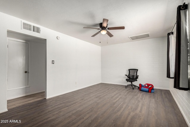 spare room featuring visible vents, ceiling fan, wood finished floors, and brick wall