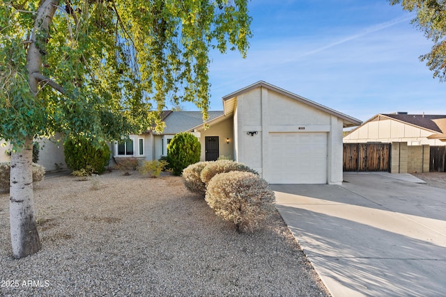 view of front facade featuring concrete driveway, fence, a garage, and stucco siding