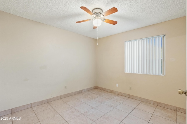 empty room with light tile patterned floors, baseboards, a textured ceiling, and ceiling fan