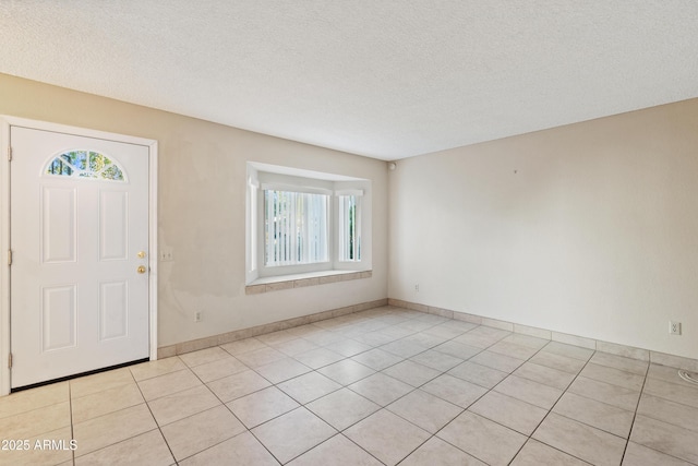 foyer featuring light tile patterned floors, a textured ceiling, and baseboards