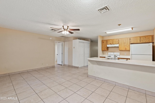 kitchen featuring visible vents, under cabinet range hood, light countertops, white appliances, and a sink