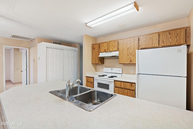 kitchen with under cabinet range hood, visible vents, white appliances, and a sink